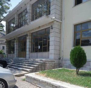 Το Πολιτιστικό Κέντρο στο κεφαλοχώρι της Βορείου Ηπείρου, τη Δερβιτσάνη, στην περιοχή του Αργυροκάστρου. Μπροστά σ' αυτή την είσοδο, πάνω στα σκαλιά, θυμάμαι, ως δημοσιογράφος που κάλυπτα την αποστολή, την πρώτη επίσκεψη Έλληνα πρωθυπουργού, το 1991 στη Βόρειο Ήπειρο, στην Αλβανία, μετά την άρση της εμπολέμου καταστάσεως που είχε γίνει το 1987. Πρωθυπουργός ήταν ο Κωνσταντίνος Μητσοτάκης και μπροστά στον εμβρόντητο Αλβανό πρωθυπουργό της εποχής εκείνης, τον Αντίλ Τσαρτσάνι, ενώπιον ενός πλήθους Βορειοηπειρωτών που είχε συρρεύσει από όλα τα γειτονικά ελληνικά χωριά του Αργυροκάστρου, της Δρόπολης, κάλεσε τον ιερέα του χωριού, τον παπά Μιχάλη Ντάκο και του έδωσε μια Εικόνα της Κοιμήσεως της Θεοτόκου. Ήμουν ακριβώς πίσω από τον Κωνσταντίνο Μητσοτάκη και δε θα ξεχάσω ποτέ εκείνη τη συγκλονιστική σκηνή, που τη ζήσαμε όσοι βρισκόμασταν εκεί με δάκρυα στα μάτια. Μέσα από το πλήθος των Ελλήνων ήρθε προς τους δυο πρωθυπουργούς ο γέροντας ιερέας, ξυρισμένος, χωρίς ράσο, κυρτωμένος από τα χρόνια και τις κακουχίες, φορώντας ένα παλιό μάλλινο σακκάκι και μια τραγιάσκα. Στην Αλβανία η θρησκεία είχε απαγορευθεί με νόμο από το 1967, αποσχηματίστηκαν οι ιερείς και οι εκκλησιές μετατράπηκαν σε σταύλους και αποθήκες. Ήταν συγκλονιστικό όταν άκουσα τον Μητσοτάκη, μπροστά στον πελιδνό Αλβανό πρωθυπουργό, να λέει στον παπαΜιχάλη, δίνοντάς του την Εικόνα: "Από σήμερα μπορείς ξανά να πας στην εκκλησία και να τη λειτουργήσεις. Σου το επιτρέπει και ο πρωθυπουργός της Αλβανίας". Είναι από τις στιγμές που μένουν ανεξίτηλα χαραγμένες στην καρδιά και στο μυαλό, σ' όλη τη ζωή σου. Γι' αυτούς τους ανθρώπους, τ' αδέλφια μας τους Βορειοηπειρώτες, αξίζει κανείς ν' αγωνίζεται..